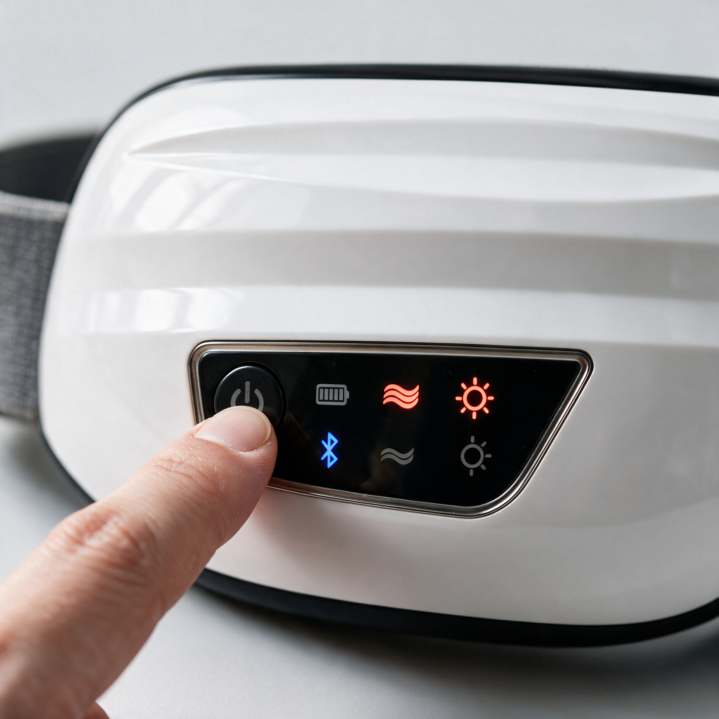 A finger pressing the power button on the Heated Eye Massager